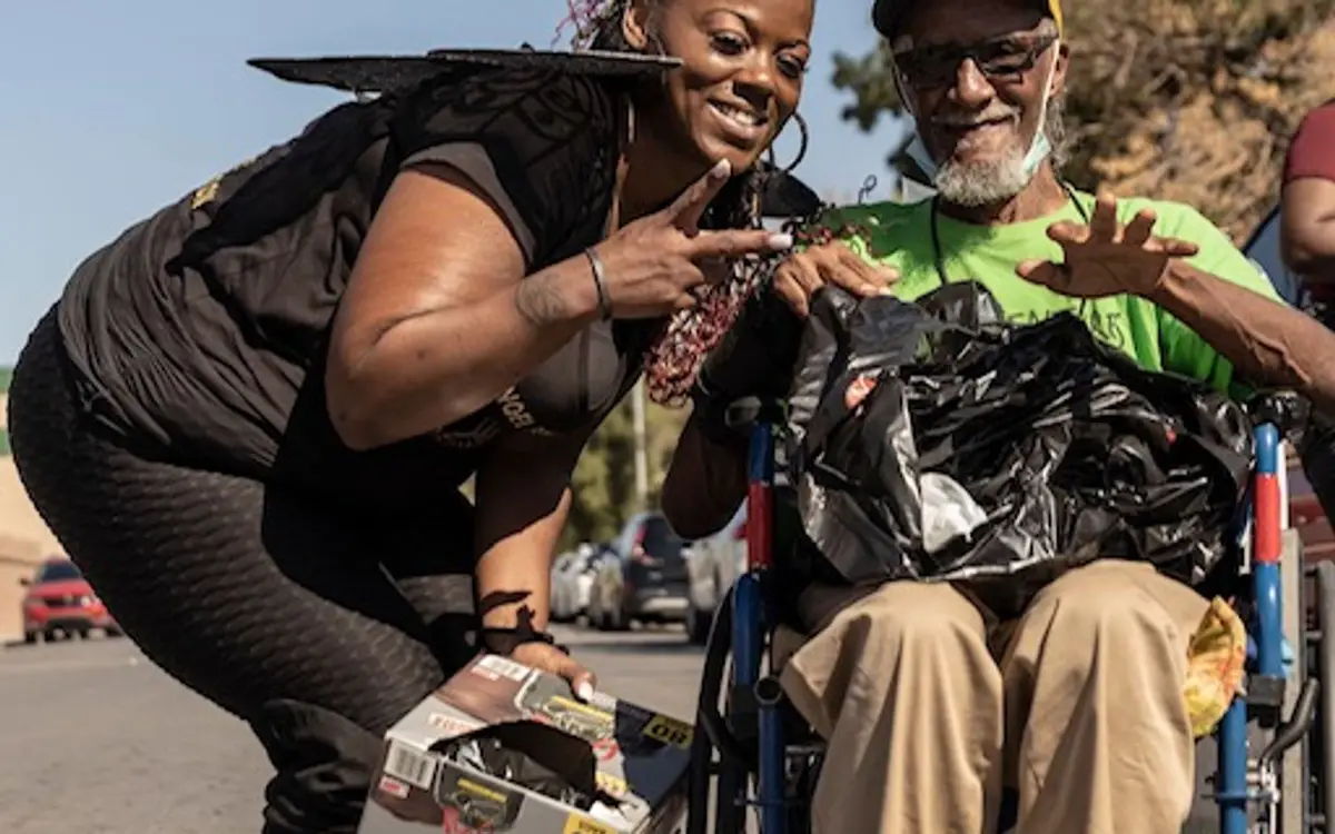 Founder smiling with a community member in a wheelchair while handing out supplies
